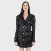 Woman wearing a black sequin party blazer with sequin lapels and cuffs, double-breasted with silver buttons, and front pockets.