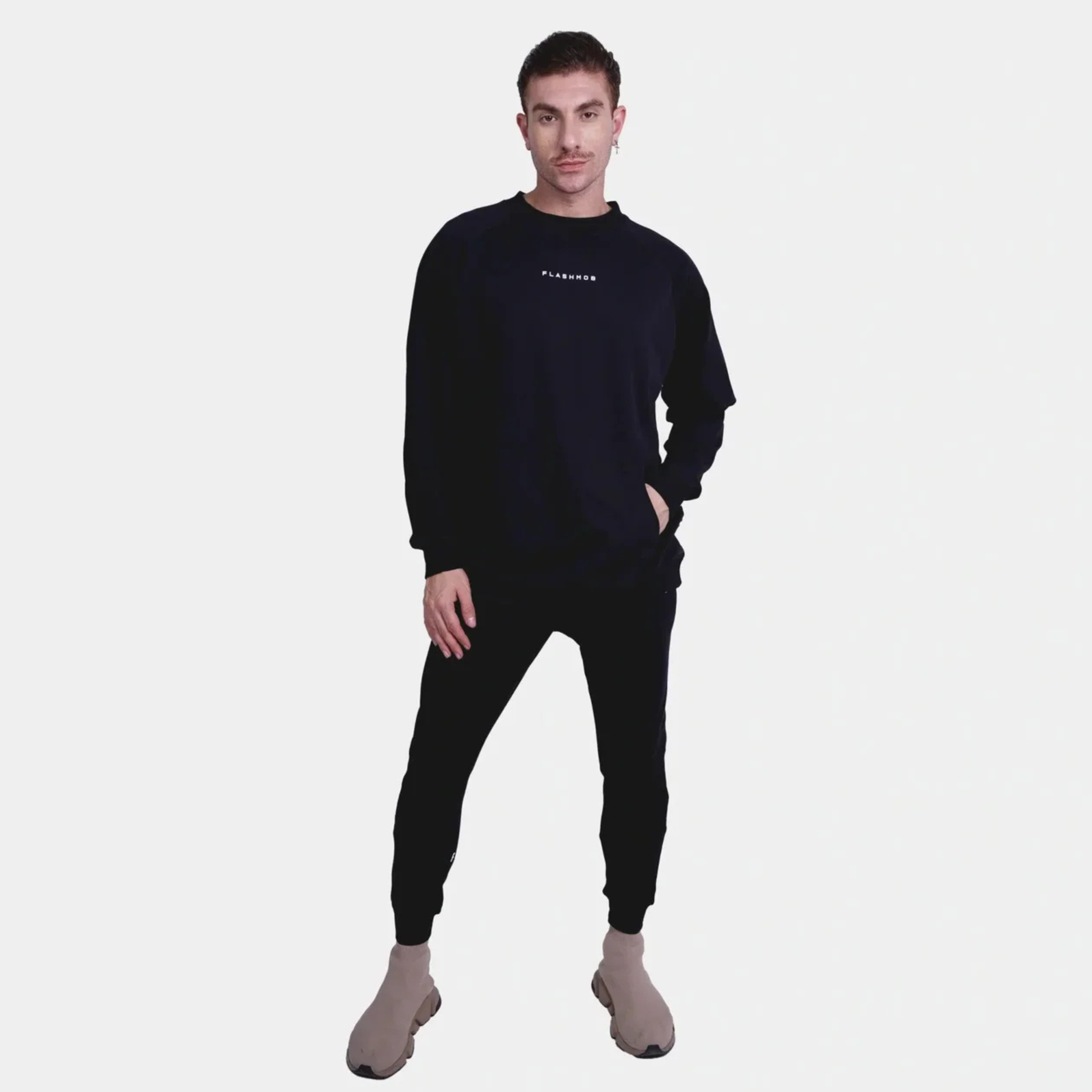 Man wearing black ultra soft oversized track set with long sleeves and jogging pants posing on white background