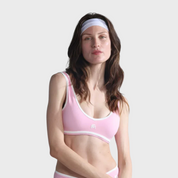 Woman wearing a pink sports bra and underwear set on a plain background