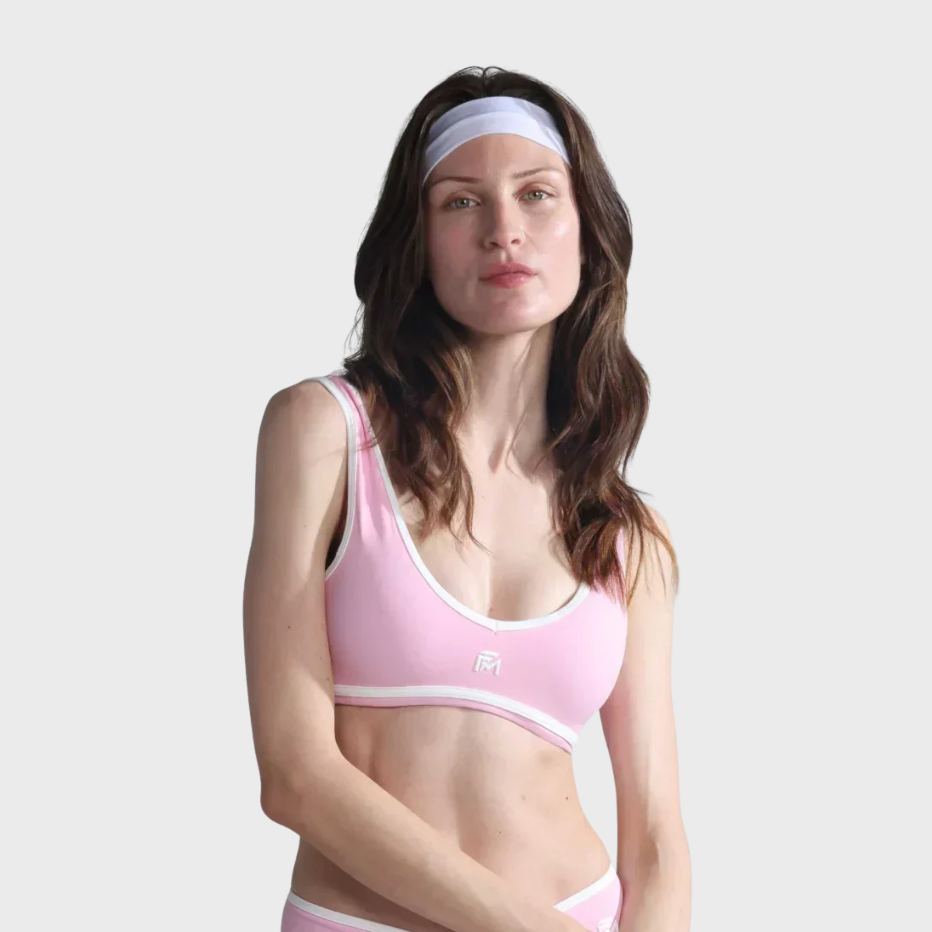Woman wearing a pink sports bra and underwear set on a plain background
