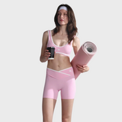 Woman in pink athletic wear holding a coffee cup and yoga mat on a white background