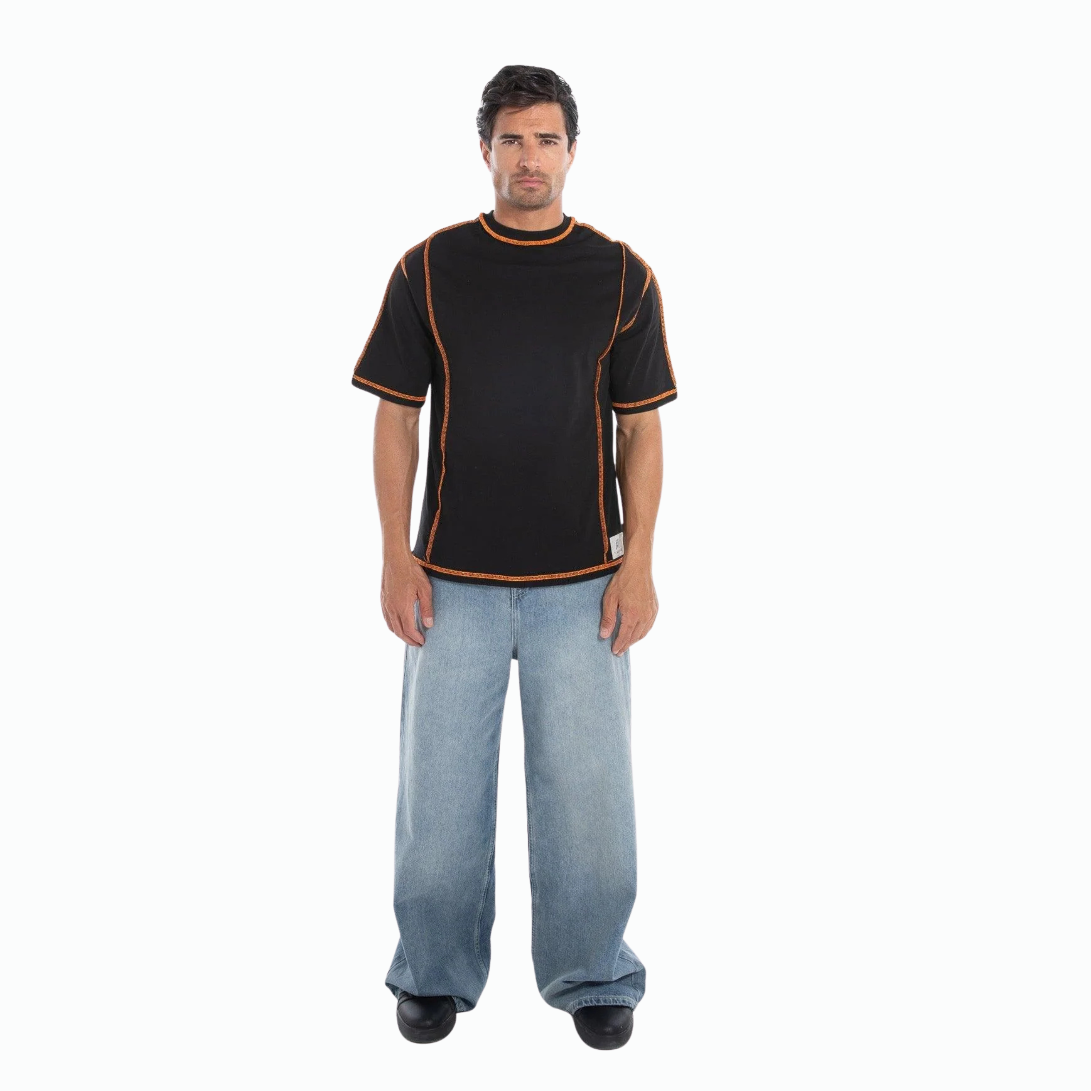 Man wearing a black t-shirt with orange accents and blue jeans on a white background