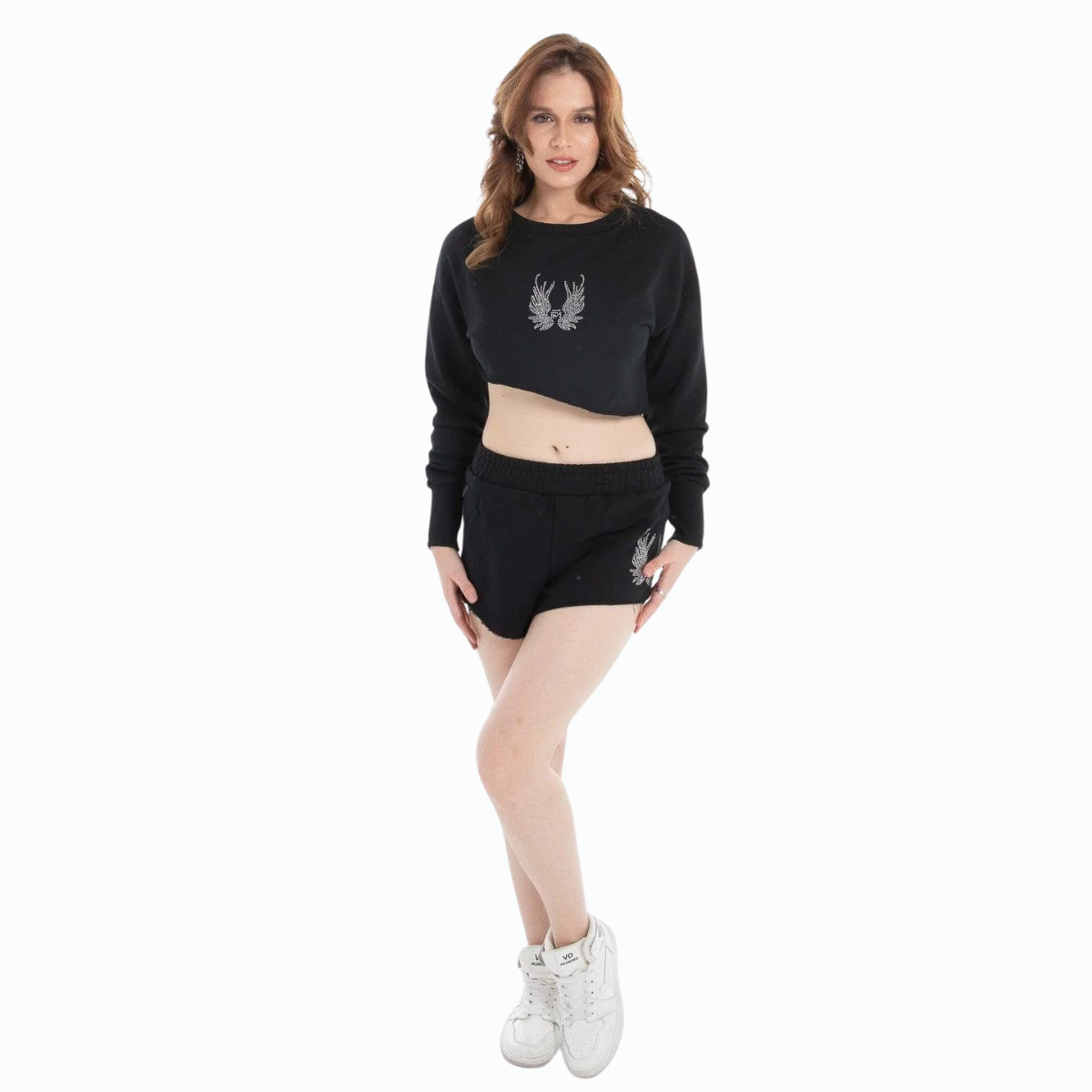 Woman wearing black cropped sweatshirt and high-waisted shorts set with white graphic design and white sneakers