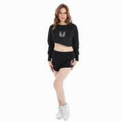 Woman wearing black cropped sweatshirt and high-waisted shorts set with white graphic design and white sneakers