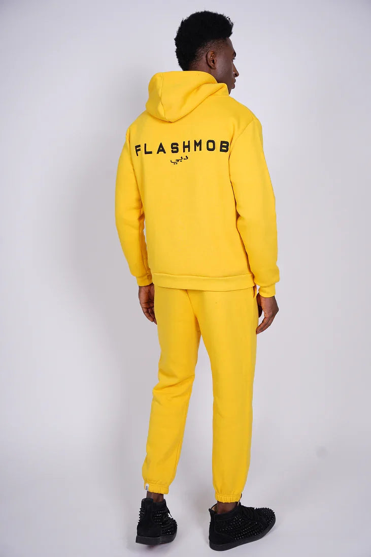 Person wearing a yellow 'FLASHMOB' tracksuit on a white background