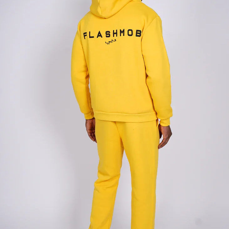 Person wearing a yellow 'FLASHMOB' tracksuit on a white background