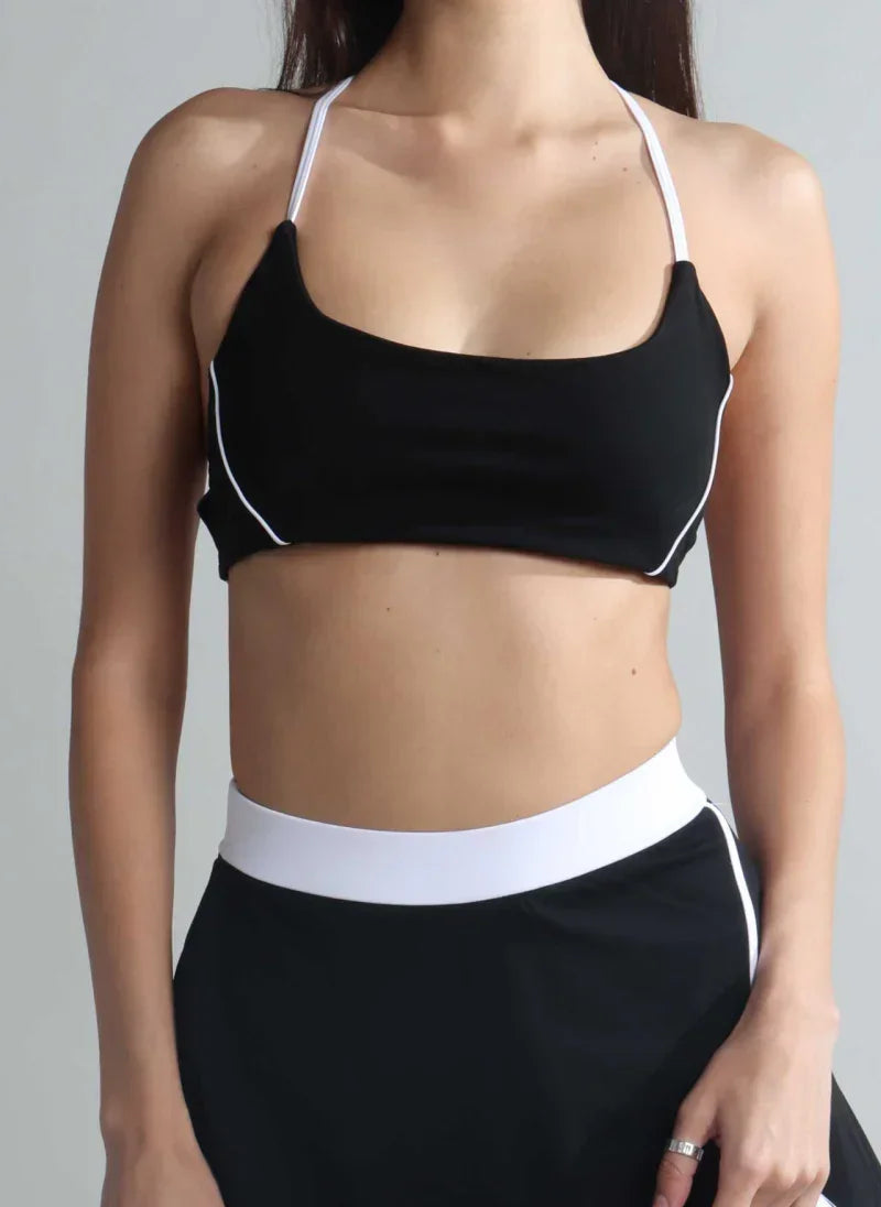 Person wearing a black sports bra with white trim on a gray background