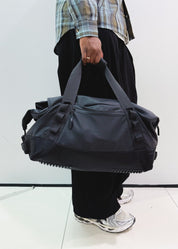 Woman carrying black convertible duffel bag by hand in streetwear style - Flashmob Nation