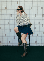 Urban lifestyle look featuring the Clove Pleated Bowling Skirt sitting on chair