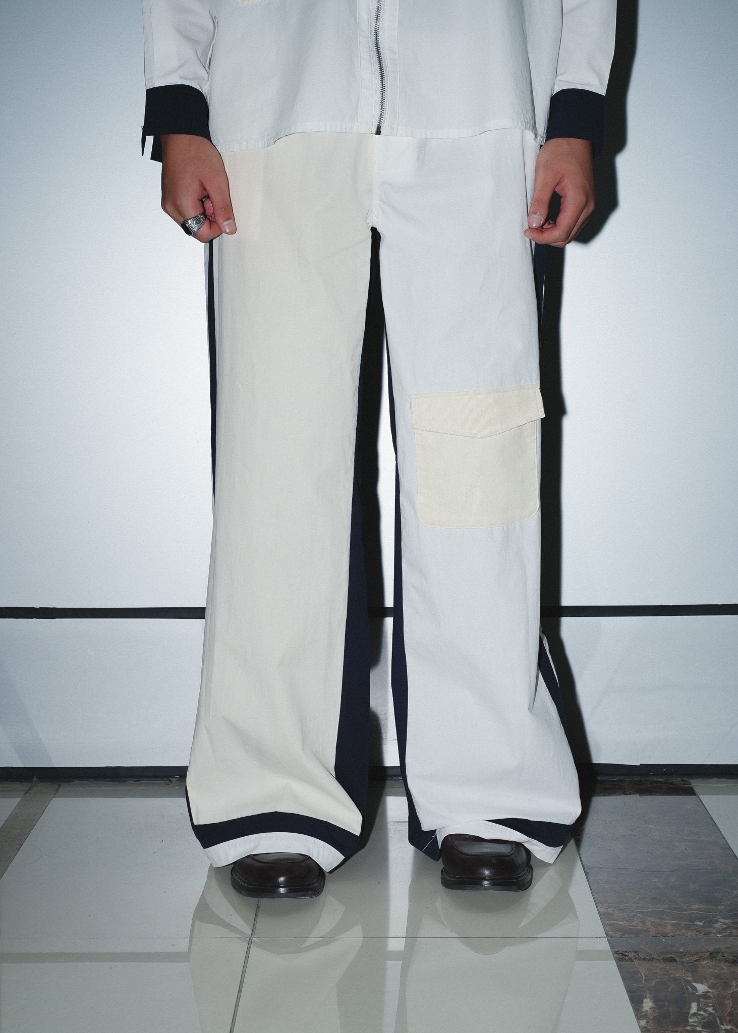 Detailed view of the architectural panelling and stitching on poplin streetwear pants.