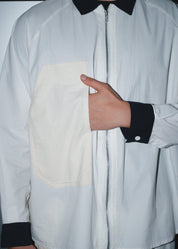 Functional side-entry pocket detail on the men's white poplin baseball shirt.