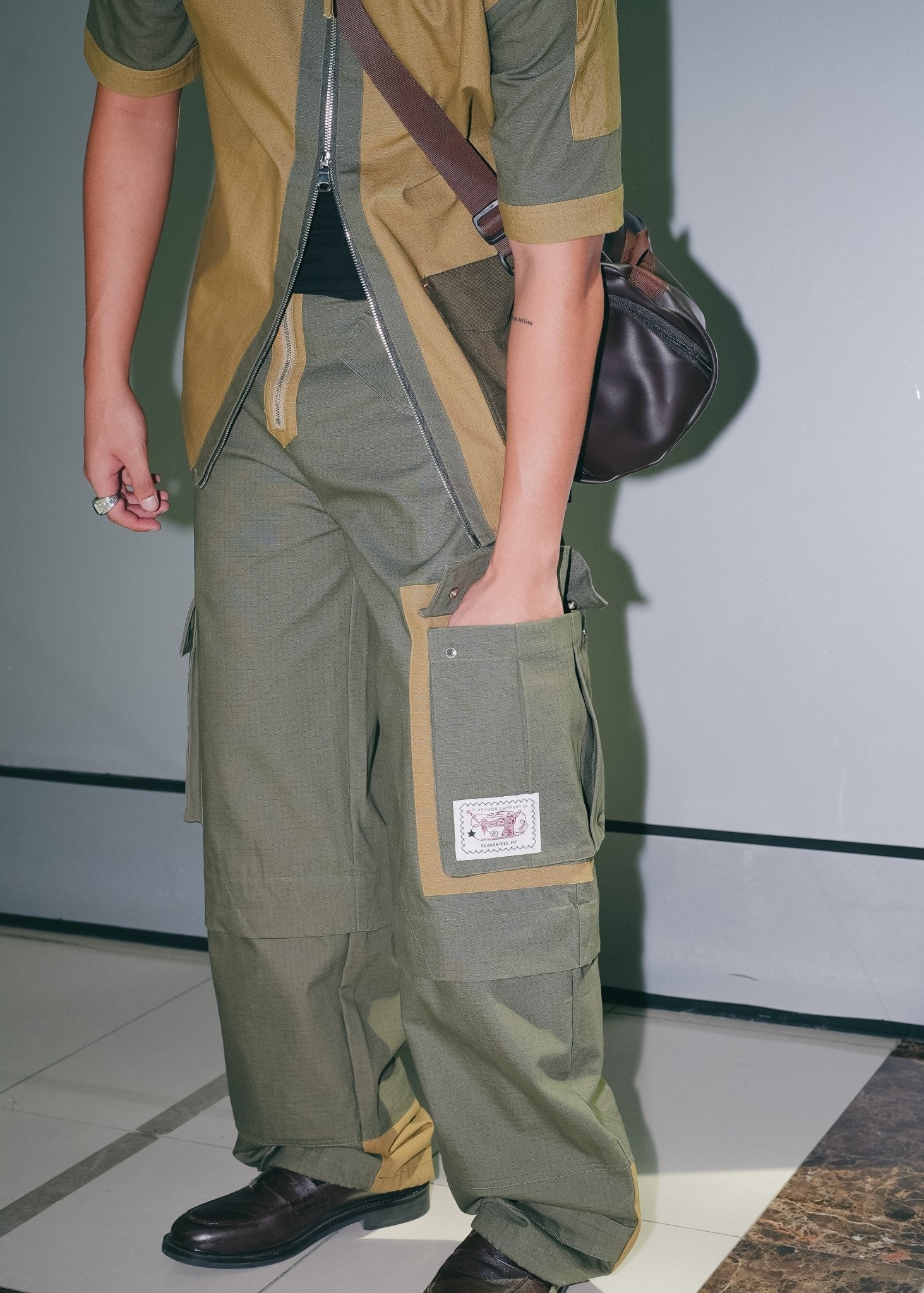 Detailed view of the olive green utility cargo pants styled with streetwear overshirt.